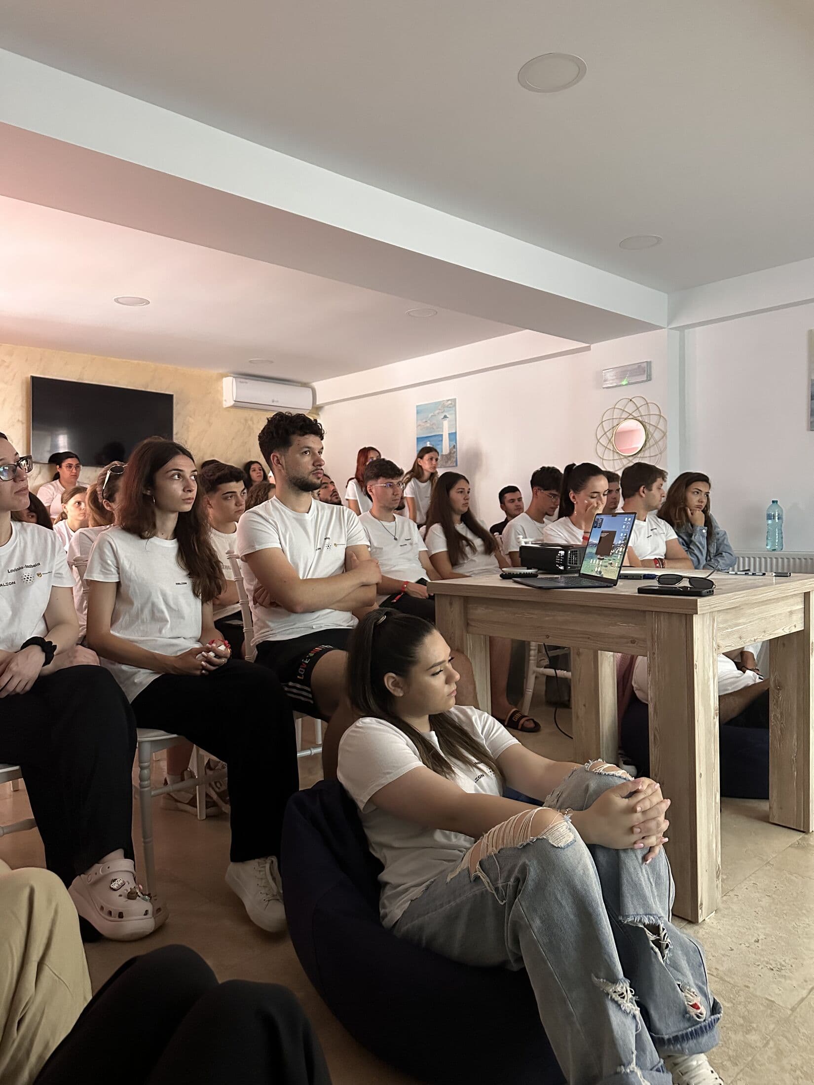 Studenți la Medicină Dentară urmărind prezentarea, așezați în sală