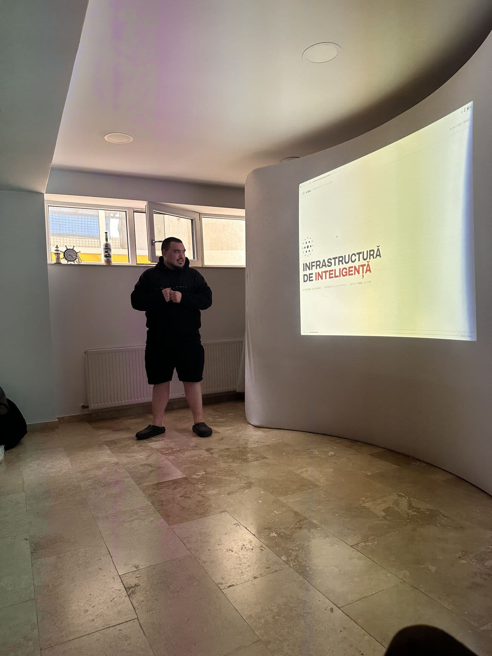 Prezentator e-data lângă ecranul de proiecție, în timpul introducerii
